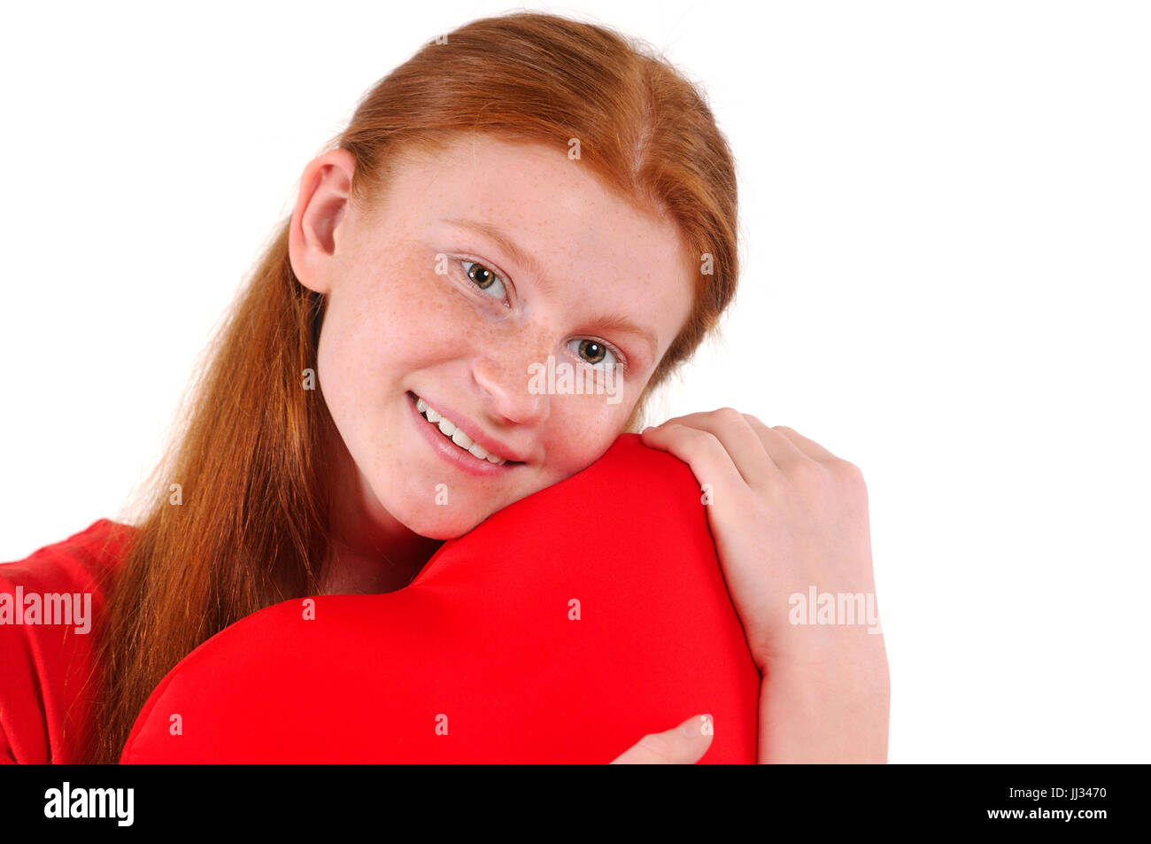Young red hair girl tenderly hug a heart shape on white background. Happy smiling lifestyle people concept. Human emotions. Stock Photo