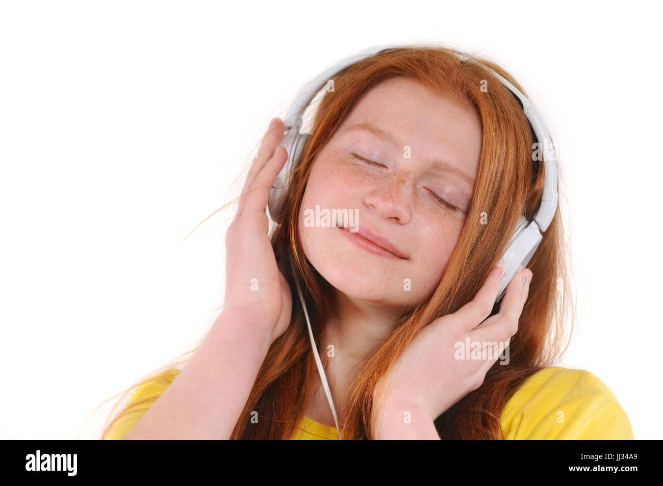Beautiful young woman with headphones relaxing by listening music. Chill out and leisure concept. Natural redhaired teenage girl. Isolated on white ba Stock Photo
