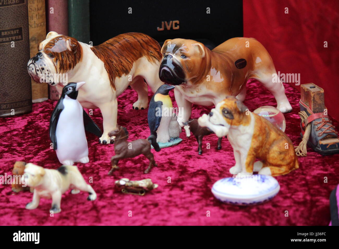 Selection of China ornaments, dogs, bulldogs and penguins displayed on red material at Portobello road market Stock Photo