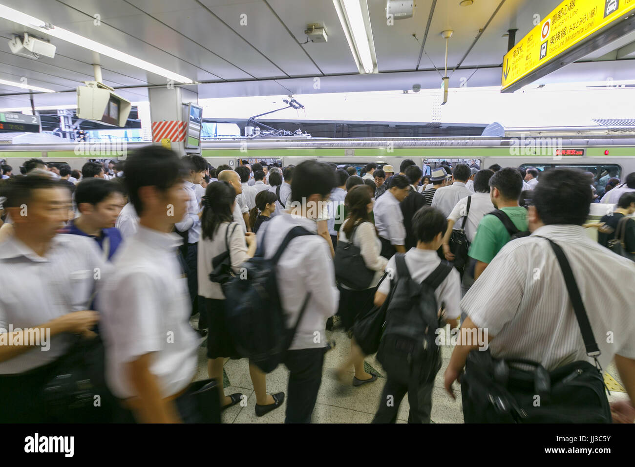 Commuters try to board the train during the peak-hour at Shibuya ...