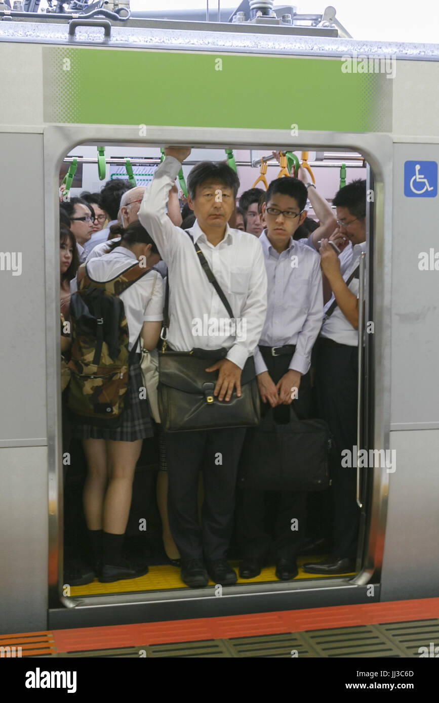 Commuters try to get into crowded train at Shibuya Station on July 18 ...