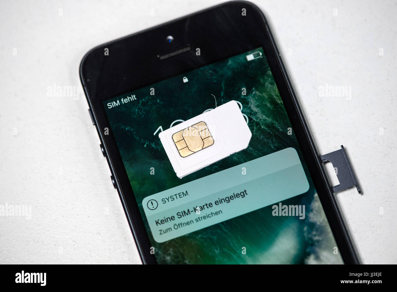 A SIM card lies on the screen of a mobile phone currently displaying a ...