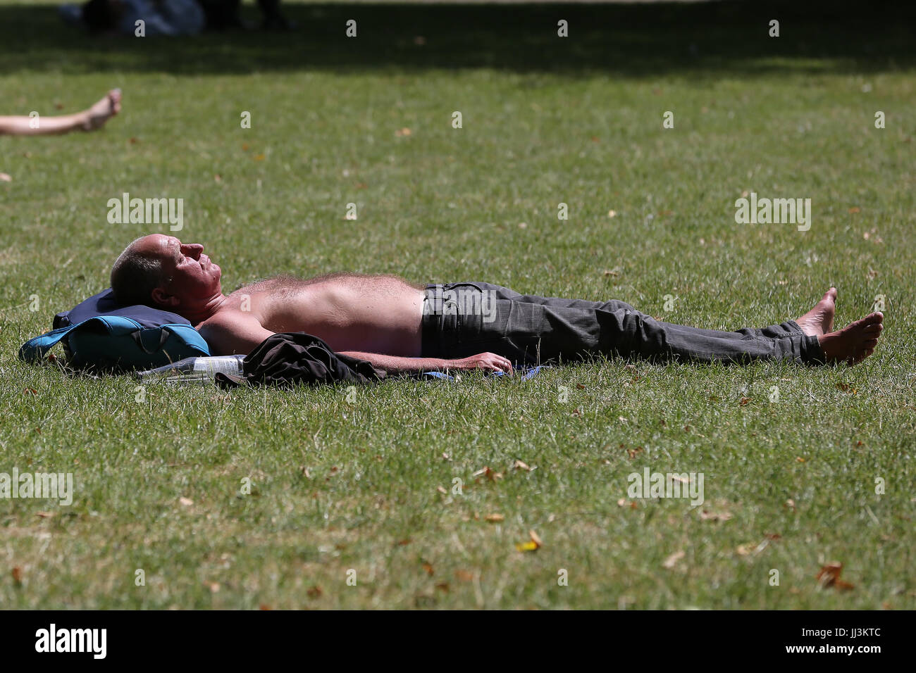 westminster-london-uk-18th-july-2017-a-man-sunbathes-on-a-hot-and