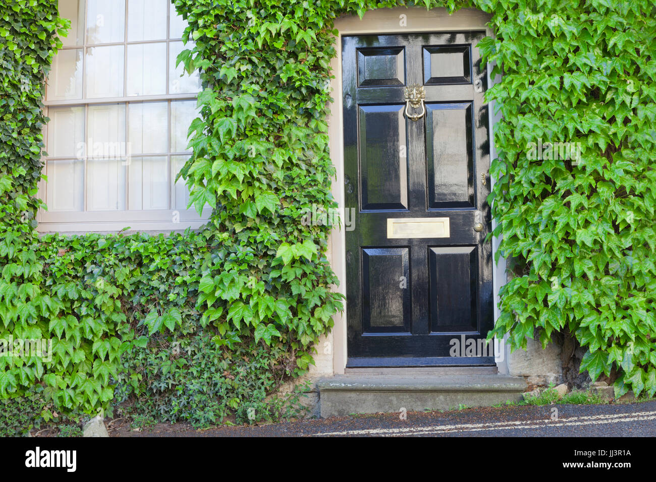Shiny black wooden doors in an old traditional English stone cottage