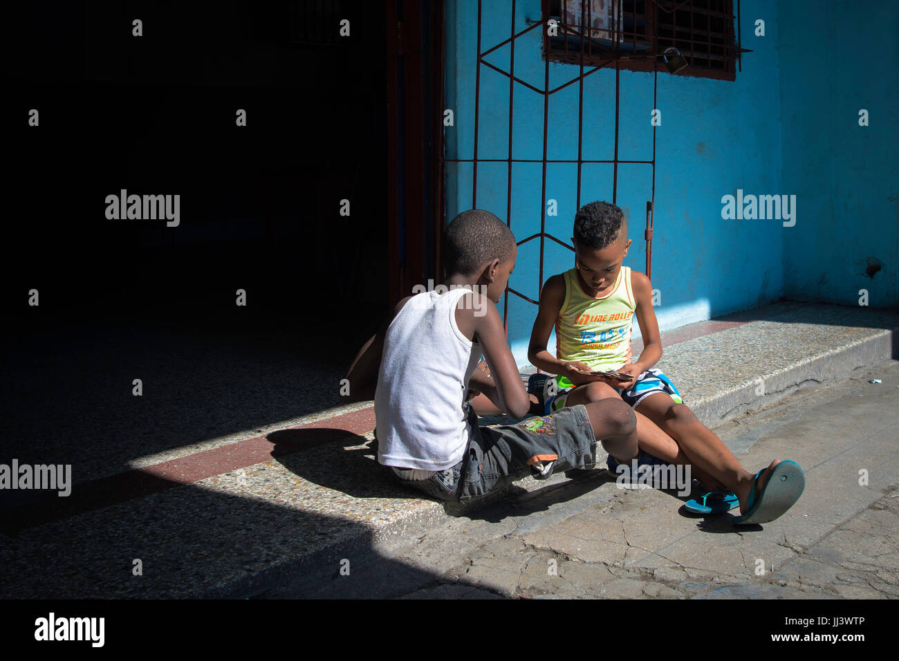 Two boys play cards along Simon Bolivar in Havana, Cuba Stock Photo