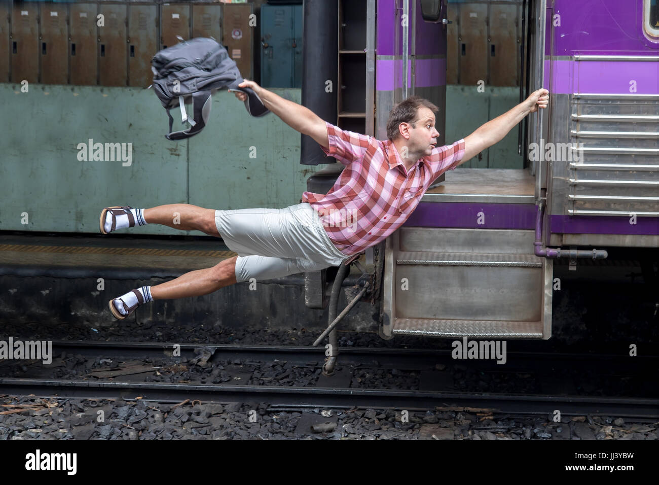 Man with backpack flies behind a moving train. Tourist holding a moving  train from a railway station. Funny traveler catches the train in motion  Stock Photo - Alamy