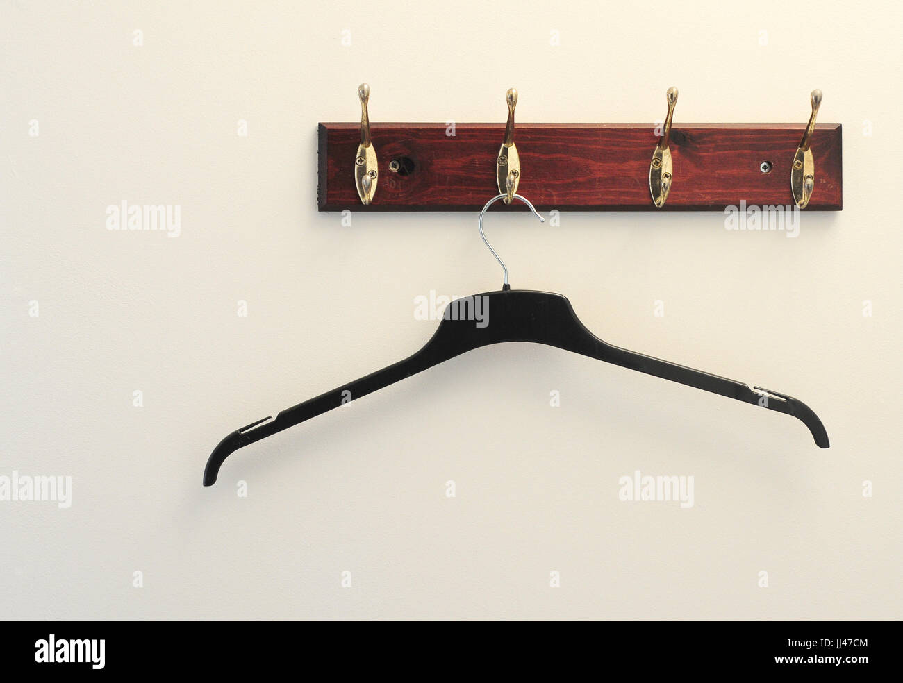 An empty clothes hanger hung on a brass coat hook Stock Photo