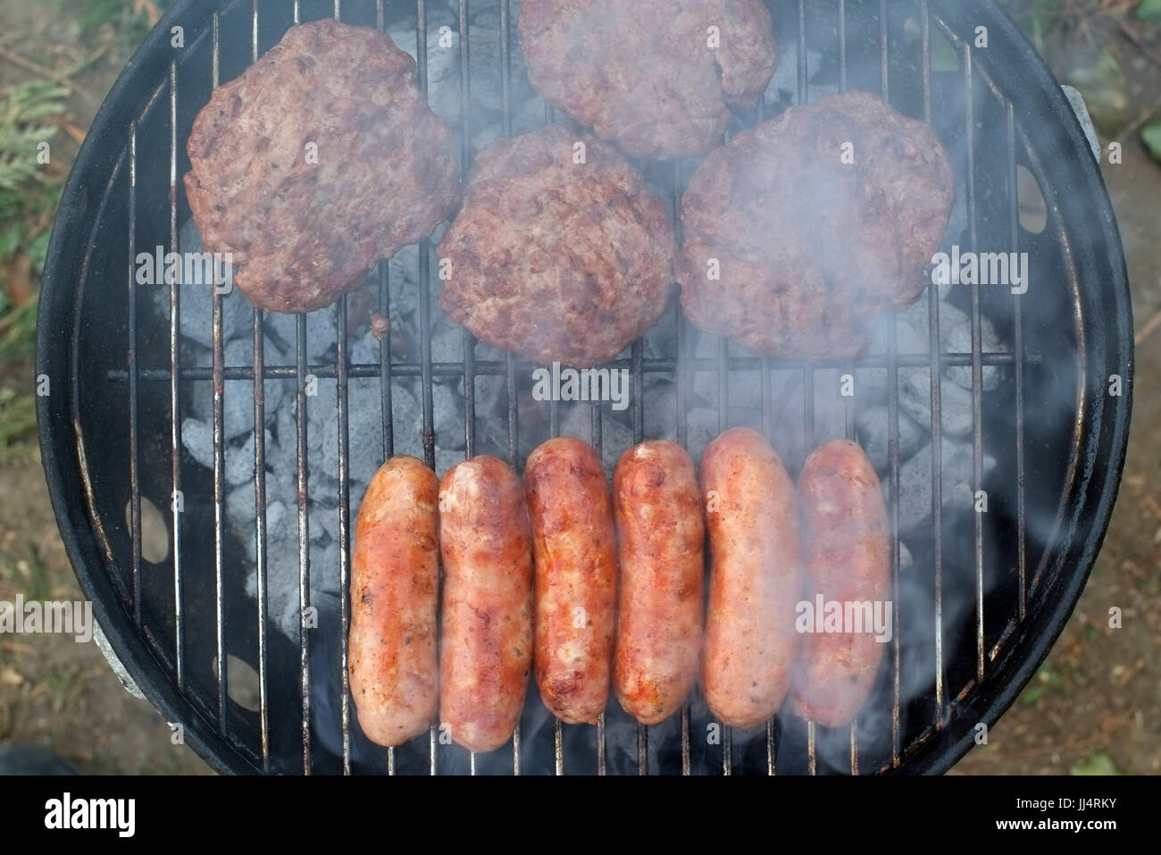 Sausages and burgers cooking on a BBQ Stock Photo Alamy