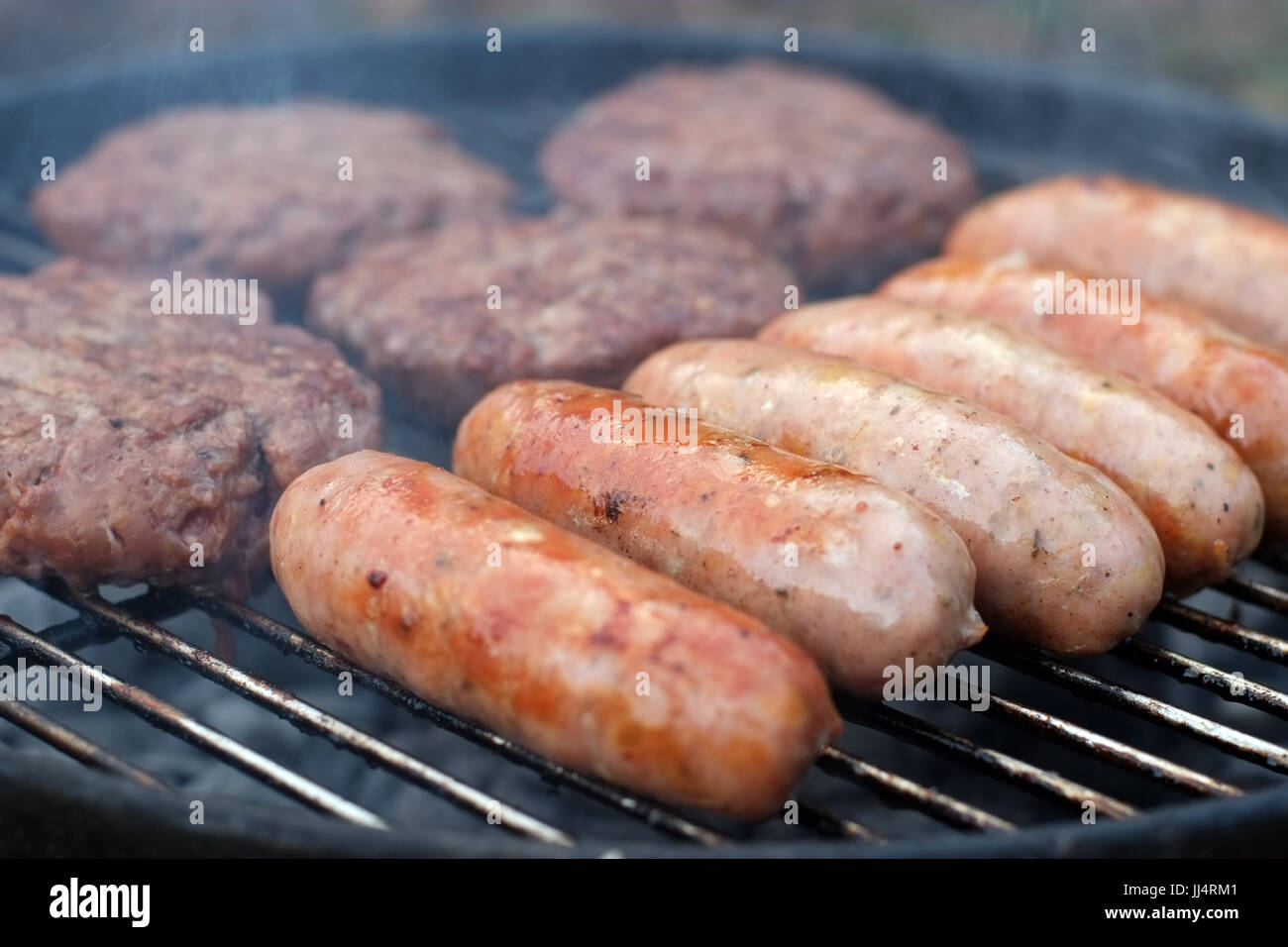 Sausages and burgers cooking on a BBQ Stock Photo Alamy