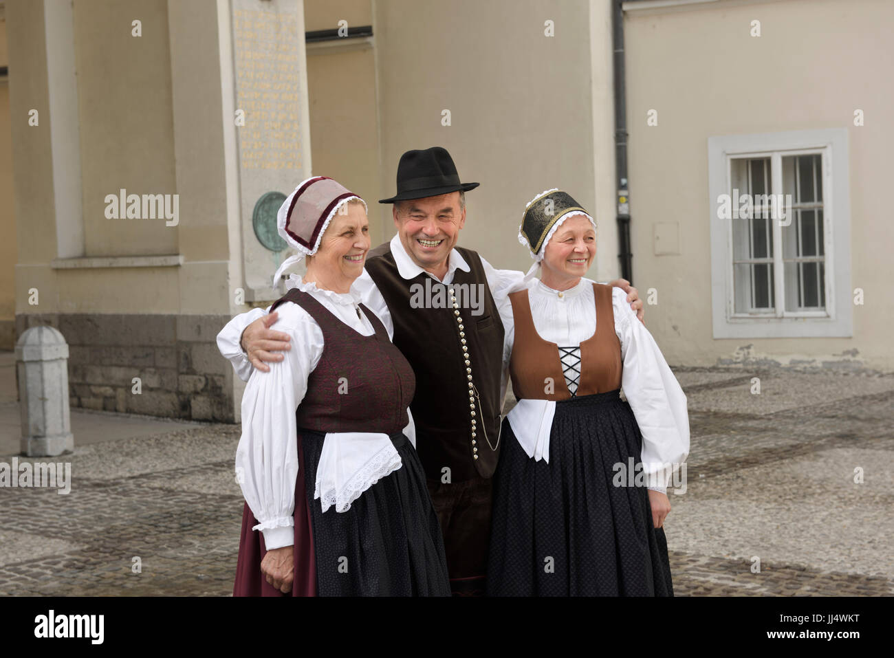 Man and two women in traditional dress standing in Pogazar Square at the Ljubljana Cathedral Slovenia Stock Photo