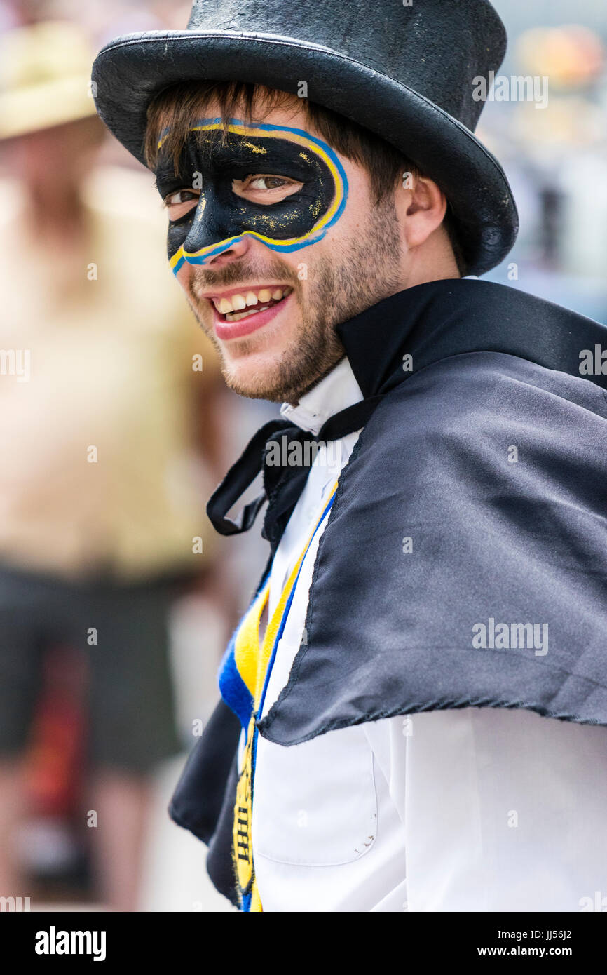 Young man, in Yateley Morris costume, with face painted in form of bandit mask, highwayman, turned to look at viewer, eye-contact, smiling. Stock Photo