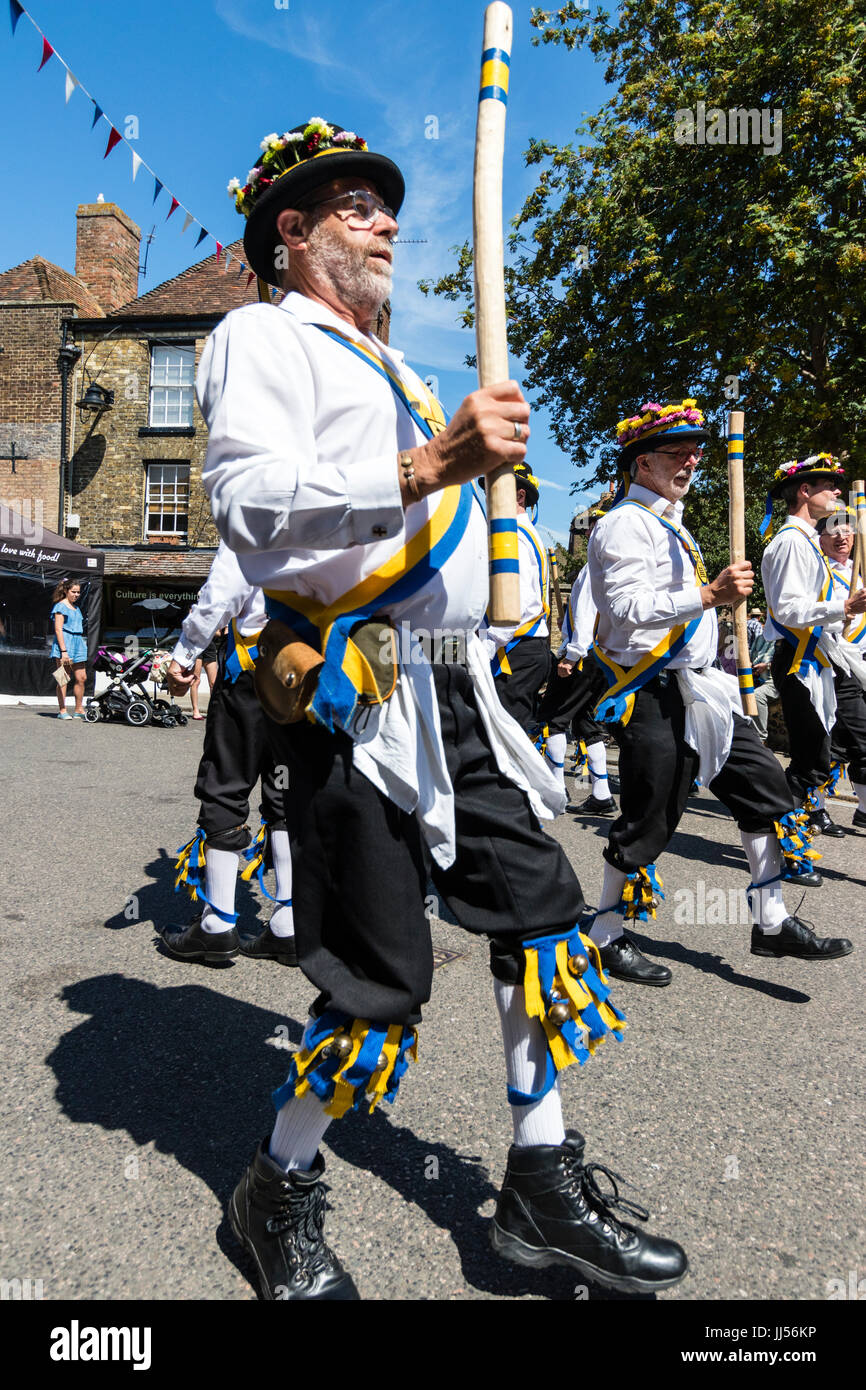 Traditional English folk dancers, Yateley Morris side dancing in the street in medieval town of Sandwich during folk and ale festival. Holding poles. Stock Photo