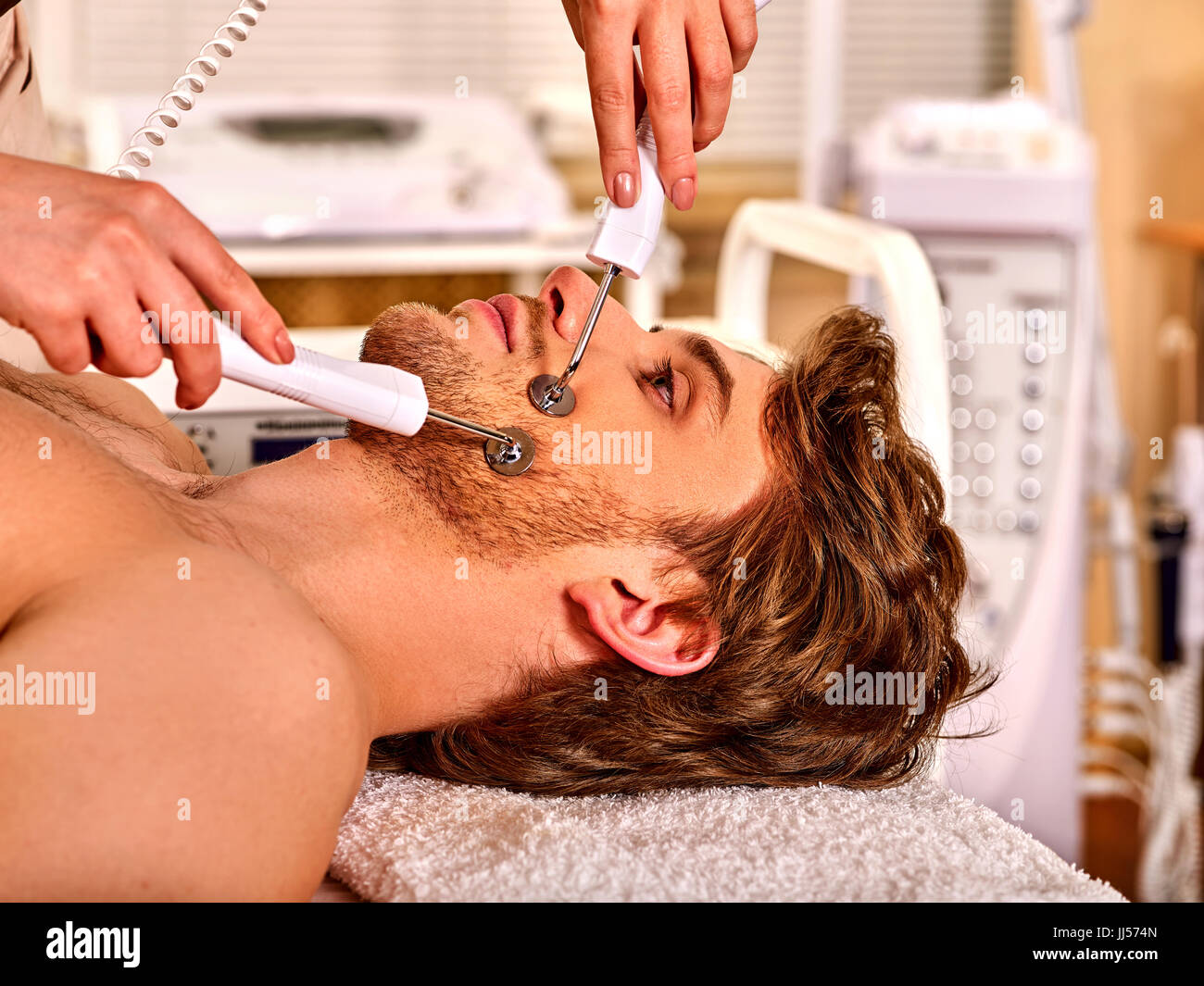 Man facial massage beauty salon. Electric stimulation man skin care . Stock Photo