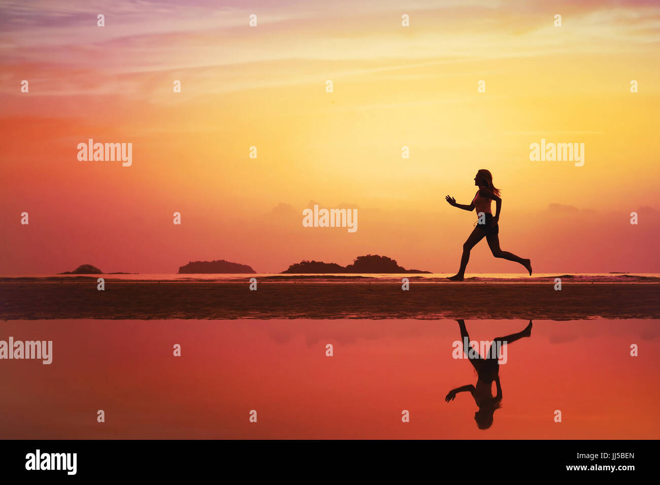 beautiful woman running on the beach at sunset, silhouette of sportive girl with reflection and place for text Stock Photo