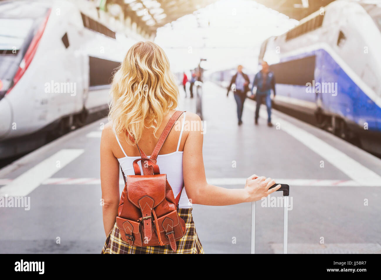 travel by train, woman passenger with suitcase waiting in railway station Stock Photo