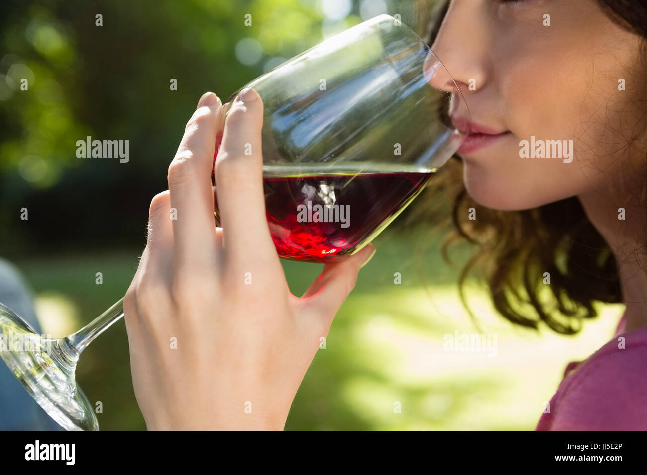 Close-up of woman drinking glass of red wine in park Stock Photo - Alamy