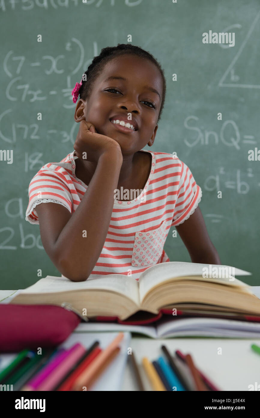 Portrait of schoolgirl reading book in classroom Stock Photo - Alamy