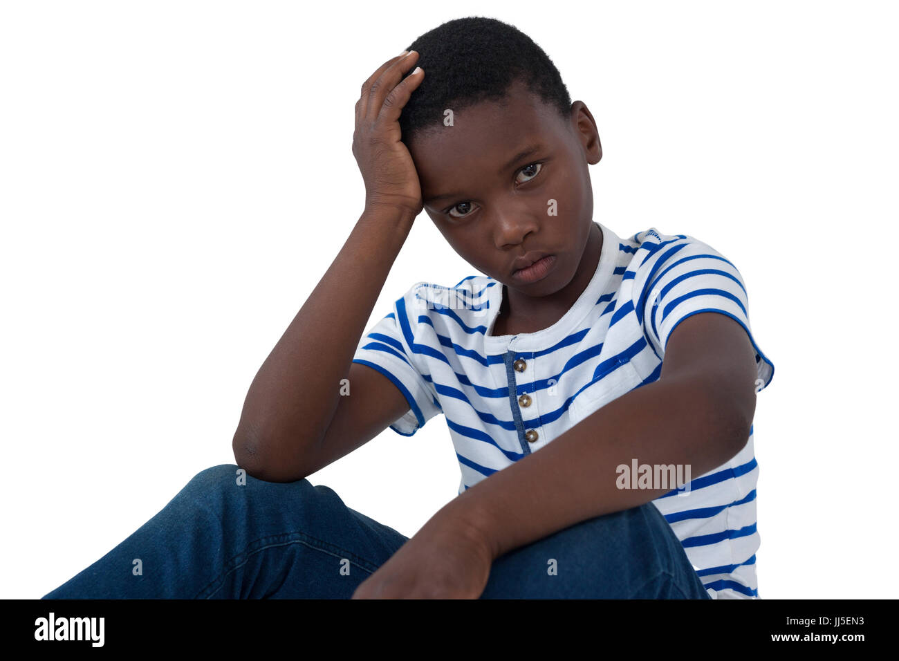 Portrait of sad boy sitting with hand on head against white background