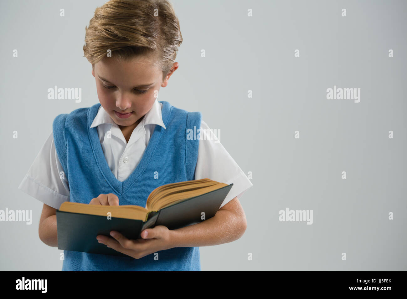 Schoolboy reading book against white background Stock Photo - Alamy