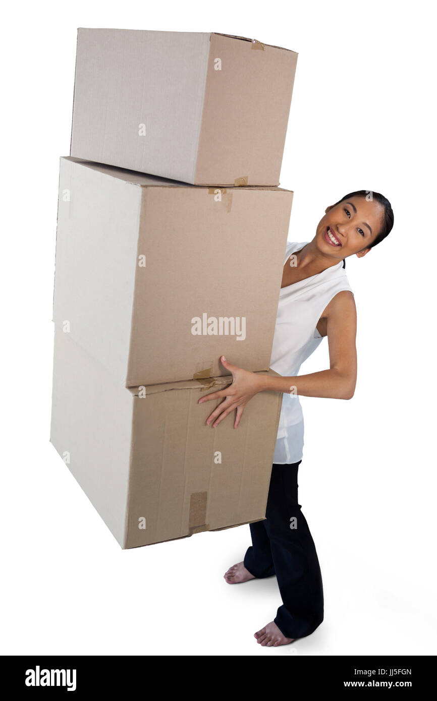 Portrait of smiling businesswoman carrying stack of cardboard boxes while standing against white background Stock Photo