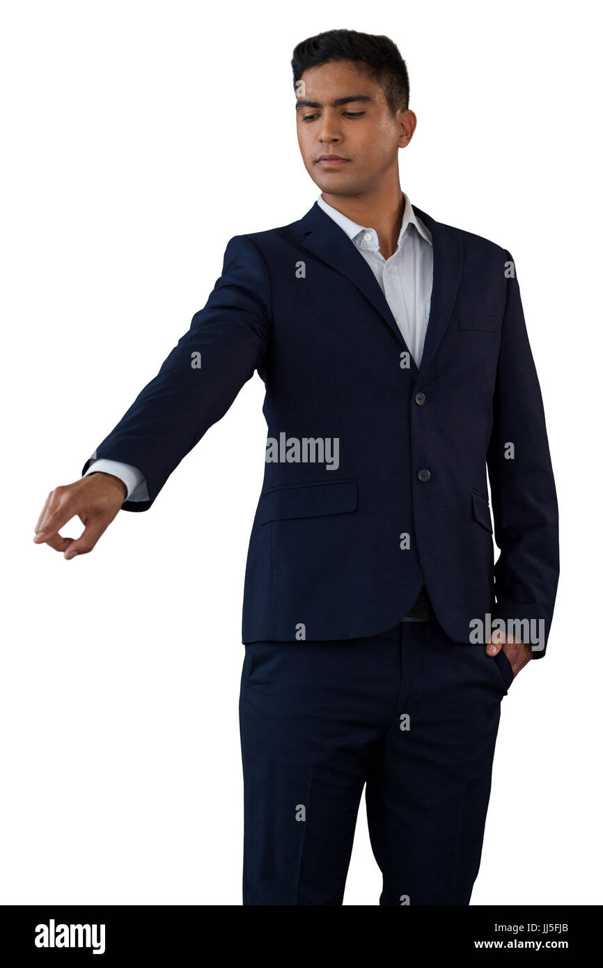 Young businessman with hands in pockets touching invisible interface