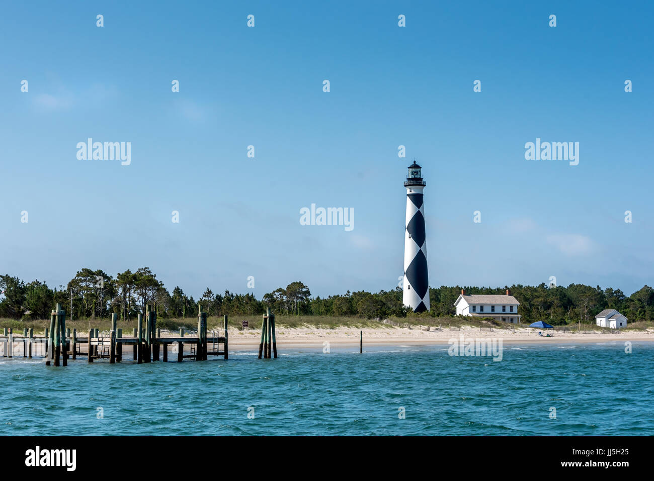 Cape Lookout Lighthouse with ferry dock on Harkers Island, North Carolina's Crystal Coast or southern Outer Banks, view from water. Stock Photo