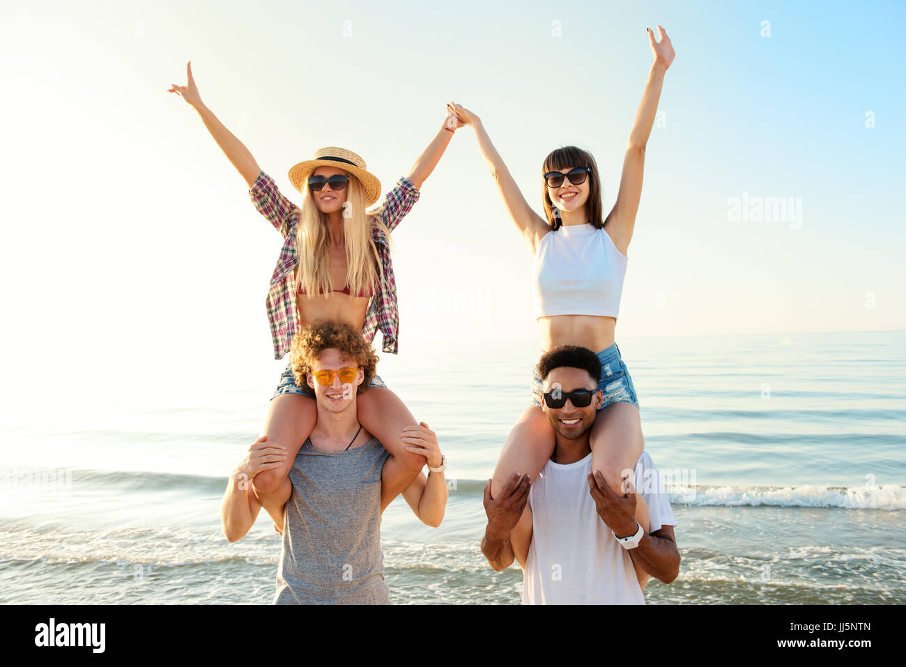 Happy smiling couples playing at the beach Stock Photo - Alamy