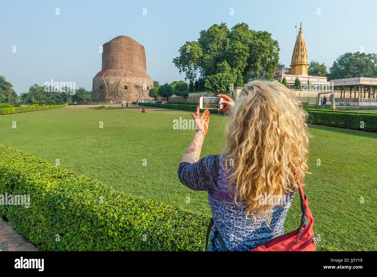 A woman taking a picture of Dhamekh Stupa in Sarnath, India with her iPhone. Stock Photo