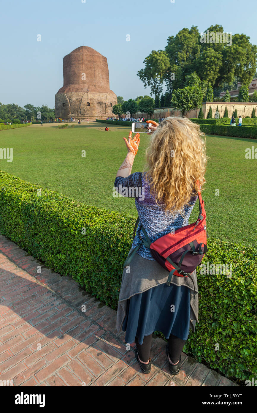 A woman taking a picture of Dhamekh Stupa in Sarnath, India with her iPhone. Stock Photo