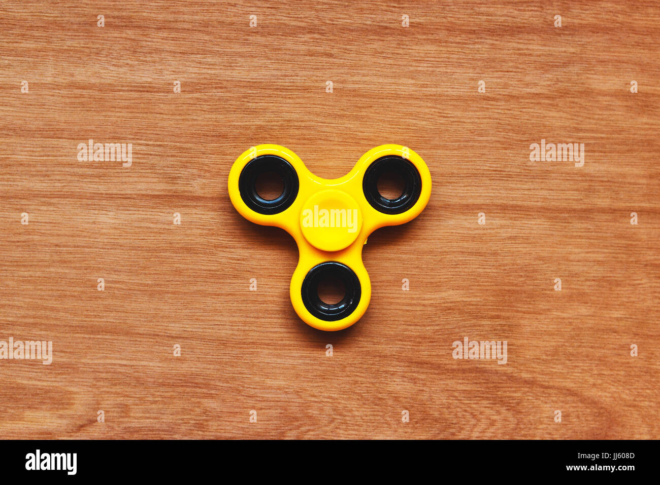 Fidget spinner toy on plywood table surface Stock Photo