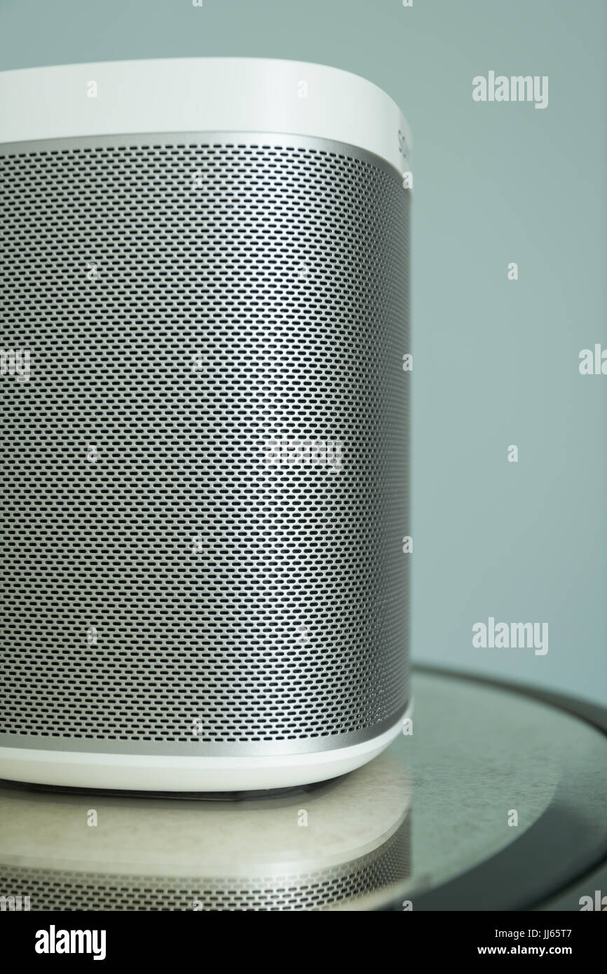 Wireless speaker on a mirrored table against a light blue background. Stock Photo