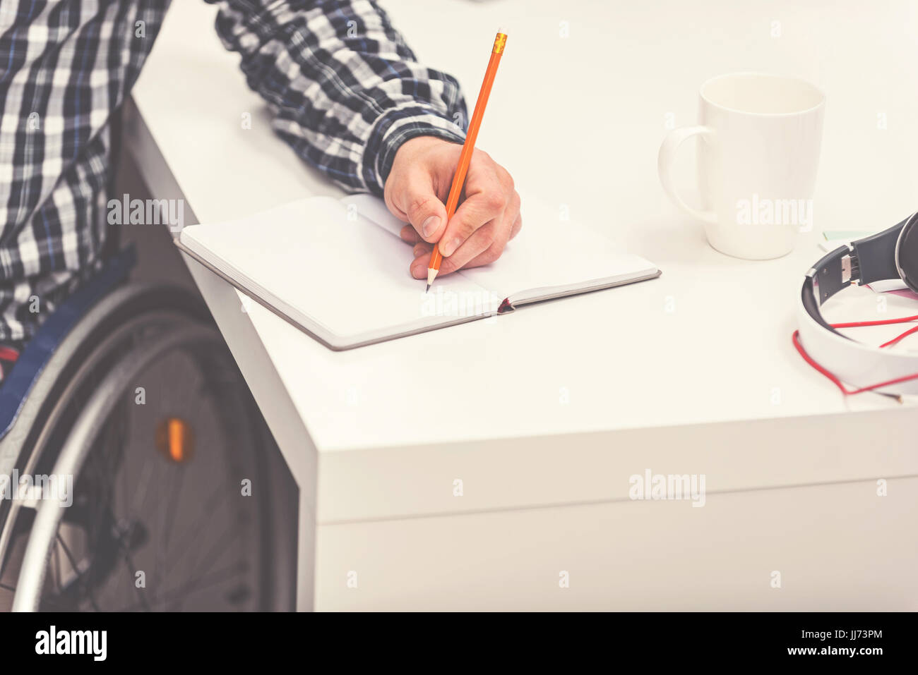 Invalid man using pencil while writing Stock Photo - Alamy