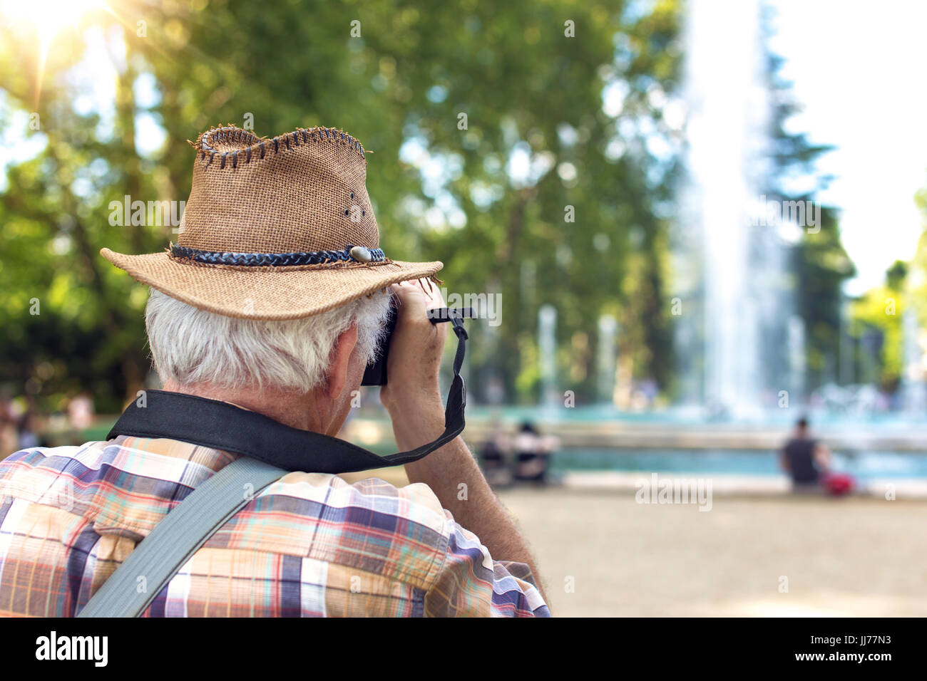 Old pensioner tourist man photographing fountain during trip Stock Photo