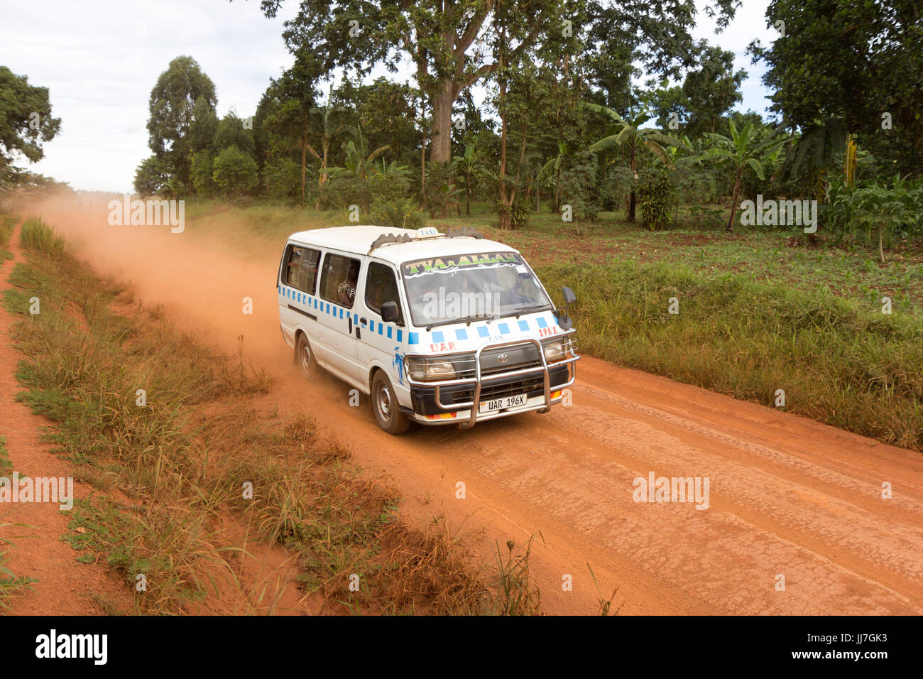 A taxi dashing by on a dirty red African road leaving a trail of dust behind it. Stock Photo