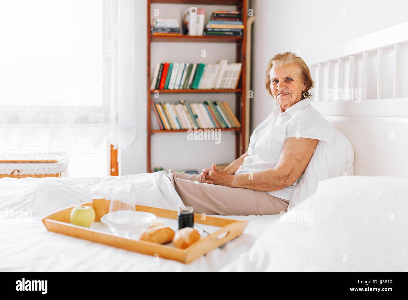 Happy elderly woman having breakfast in bed Stock Photo