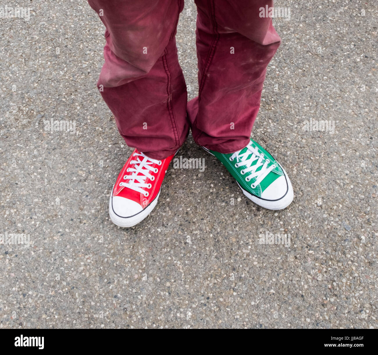 A man wearing brightly coloured plimsolls, pumps or trainers, one red and  one green, taken looking down on his feet Stock Photo - Alamy
