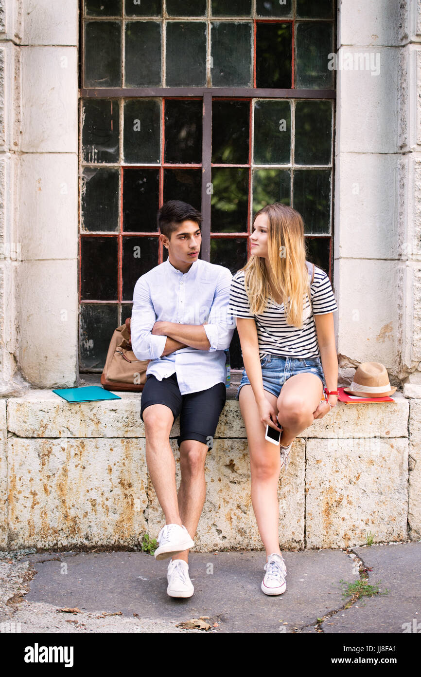Attractive teenage student couple posing in front of university. Stock Photo