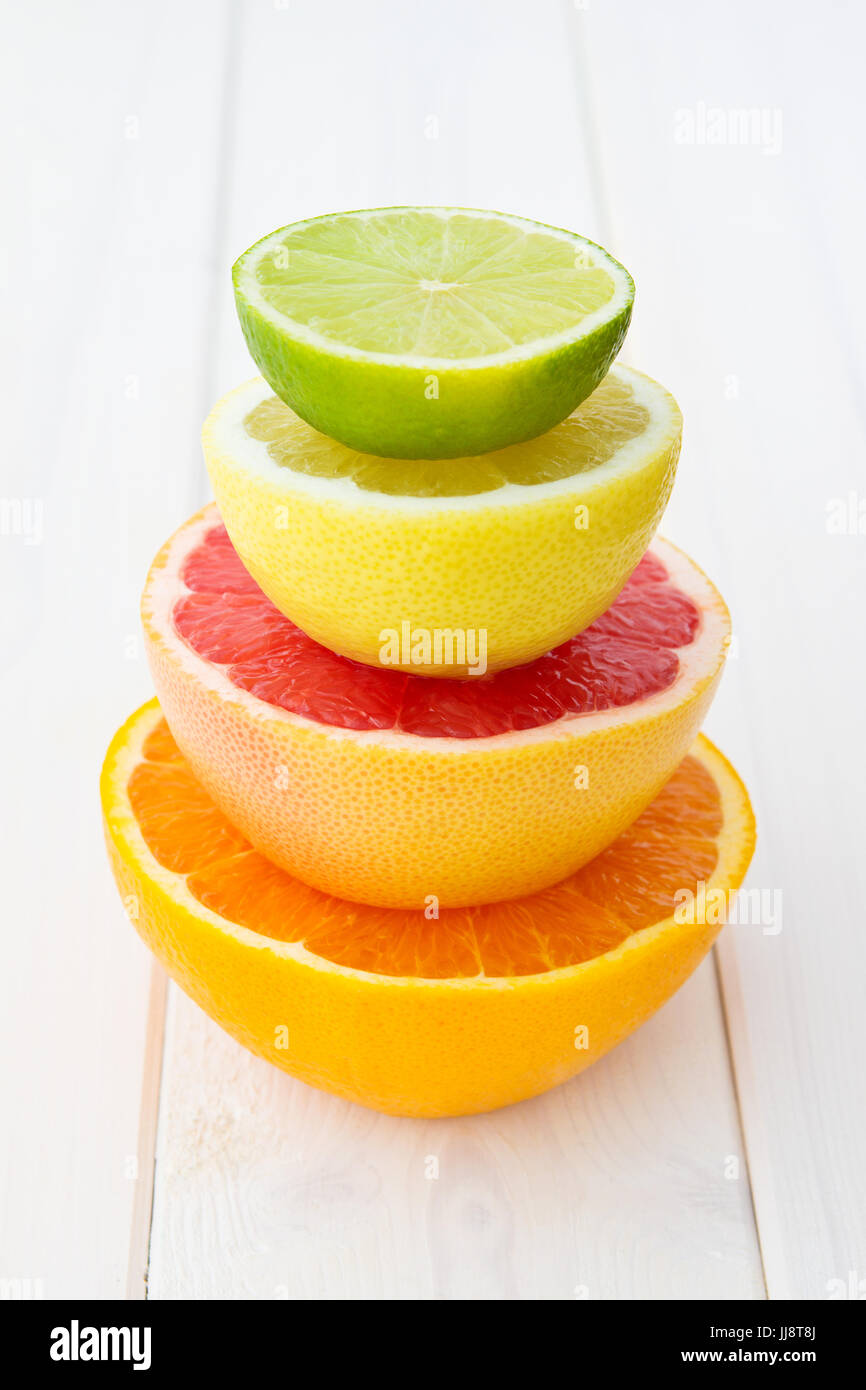 Tower of fresh cut orange, grapefruit, lemon and lime on bright wooden table Stock Photo