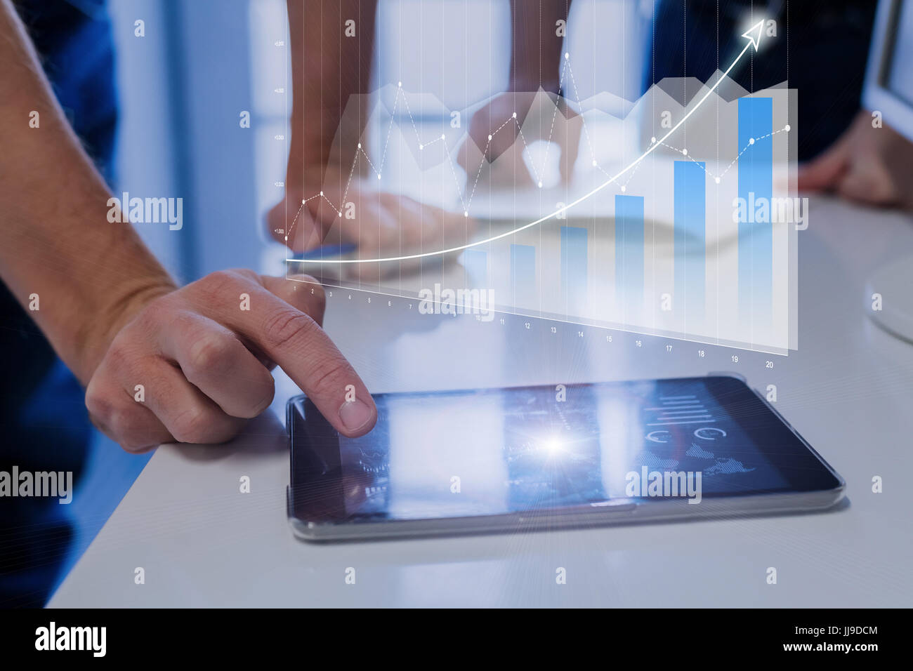 Augmented reality (AR) financial charts showing growing revenue floating above digital tablet computer screen, two businessmen having meeting about st Stock Photo