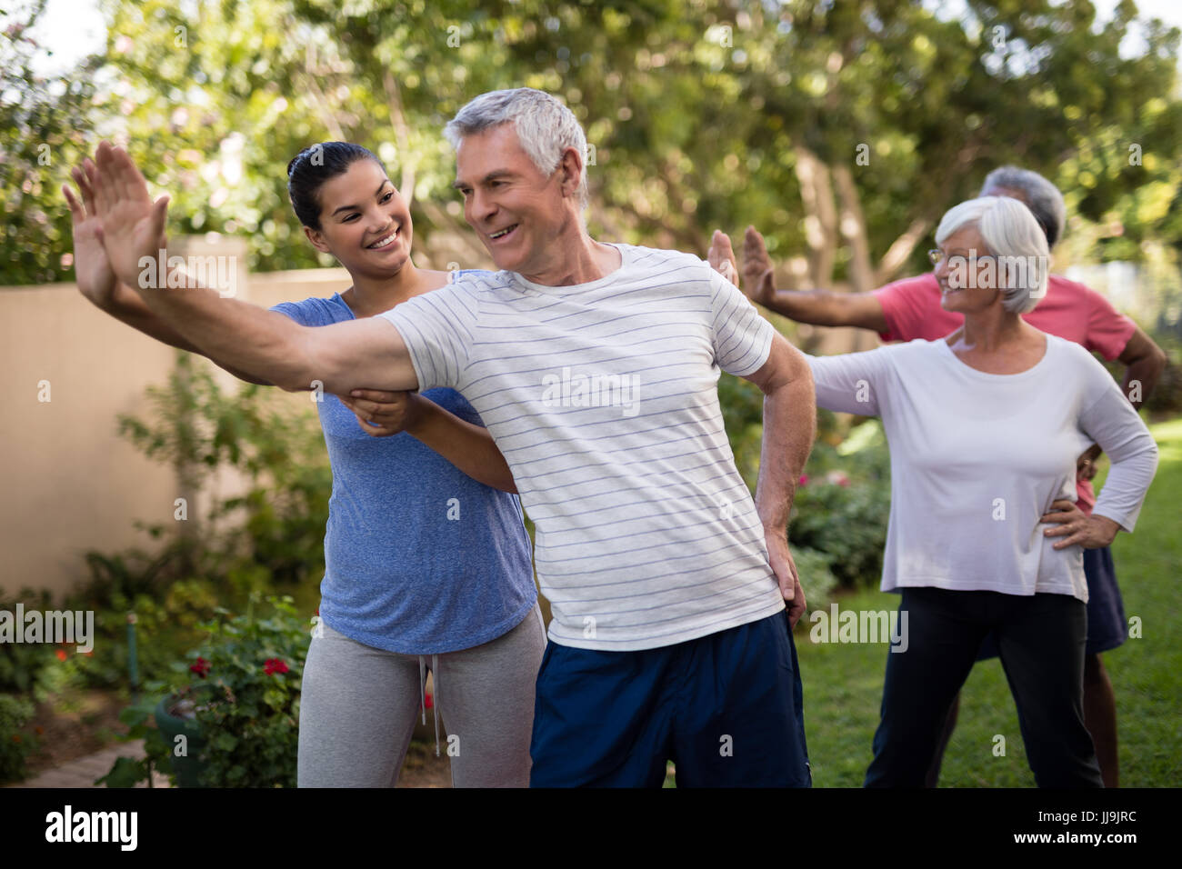 Happy trainer teaching senior people while exercising in park Stock ...