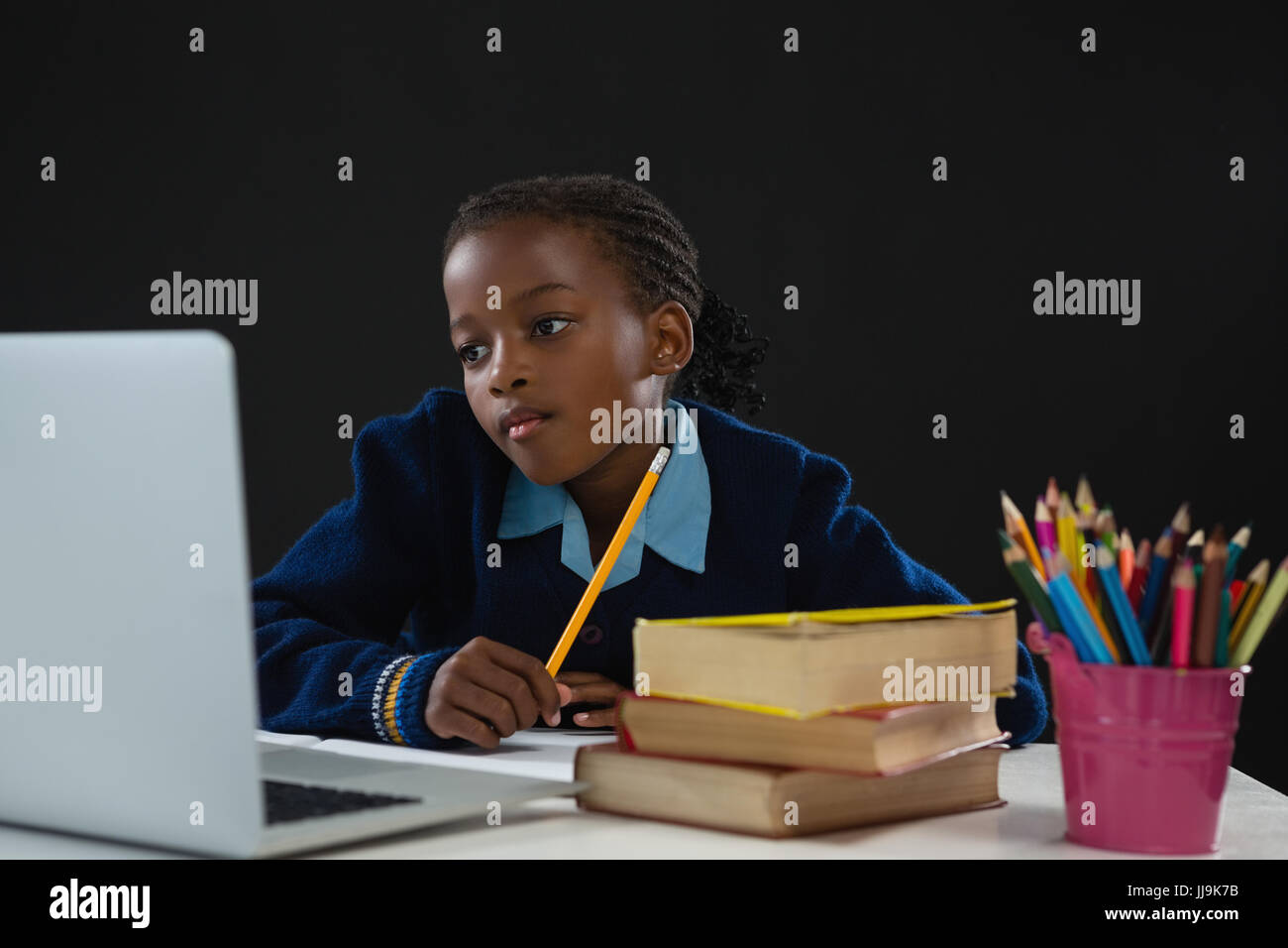 Schoolgirl looking at laptop against black background Stock Photo - Alamy