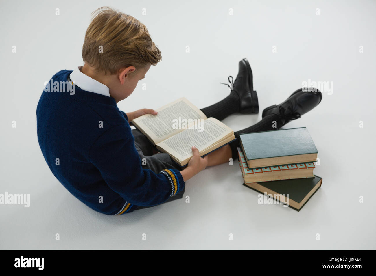 Attentive schoolboy reading book on white background Stock Photo - Alamy