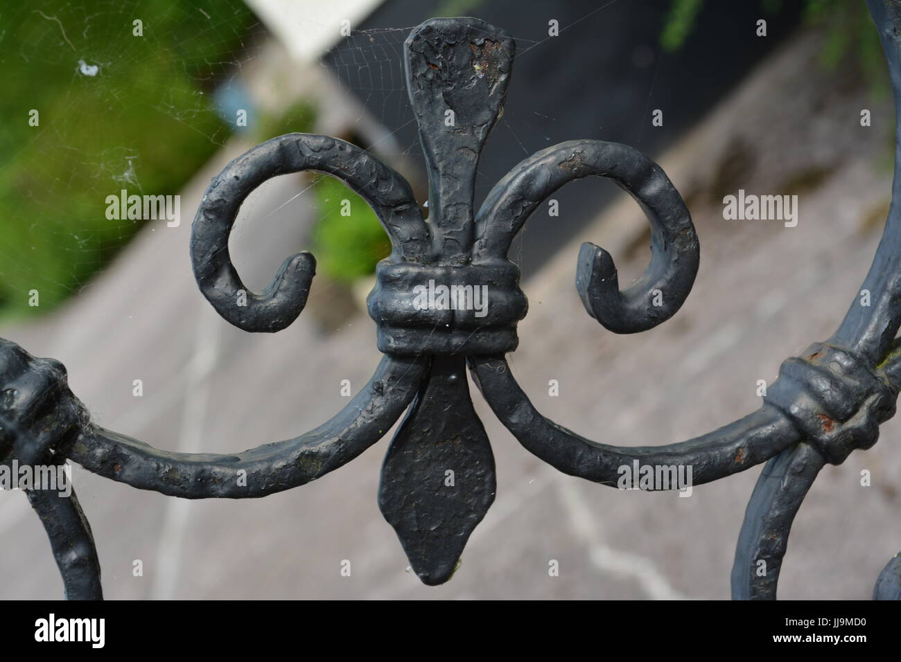 Fleur de lis lys close up detail of weathered black painted decorative metal gate re architecture design wrought iron work heritage Stock Photo