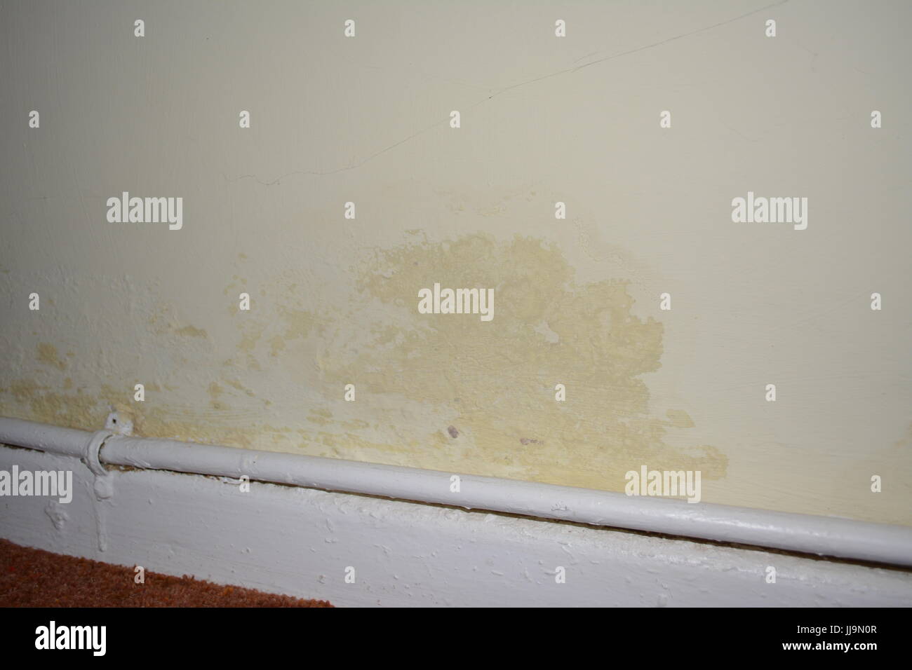Rising damp on inside wall of old house re peeling paint poor decoration DPC DPM damp proof course membrane lack of heating pipework and heating pipes Stock Photo