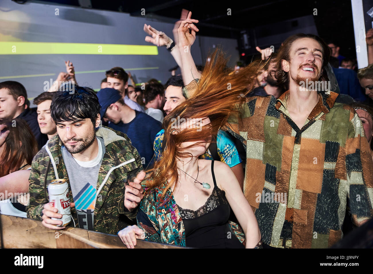BRISTOL, UK - DECEMBER 2016: A young, attractive woman whips her hair over her face as she dances in a crowd at a nightclub on December 4, 2016 Stock Photo