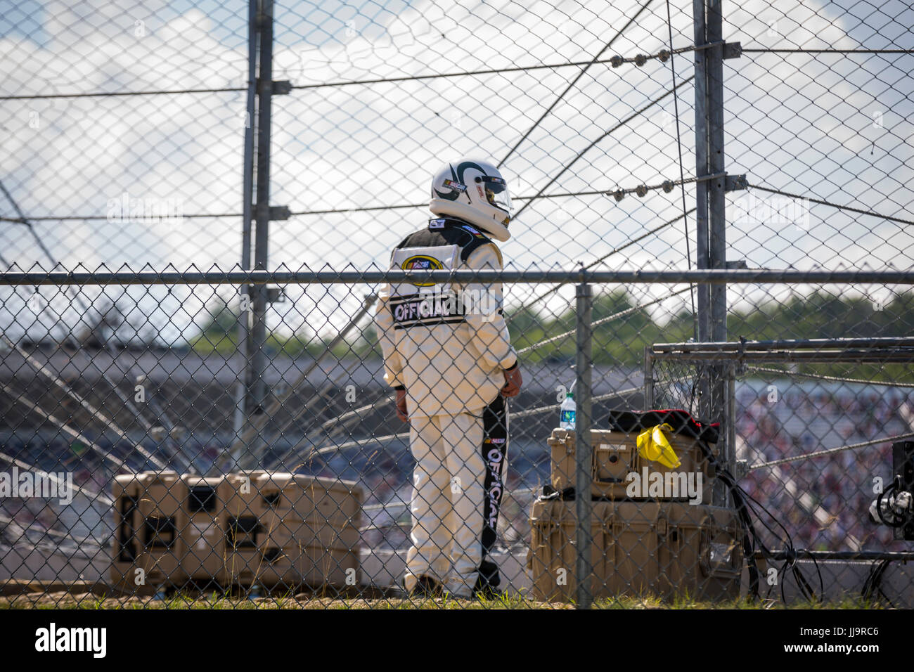 A race official watches the NH 301 NASCAR Sprint Cup race from outside the fence at the New Hampshire Motor Speedway. Stock Photo