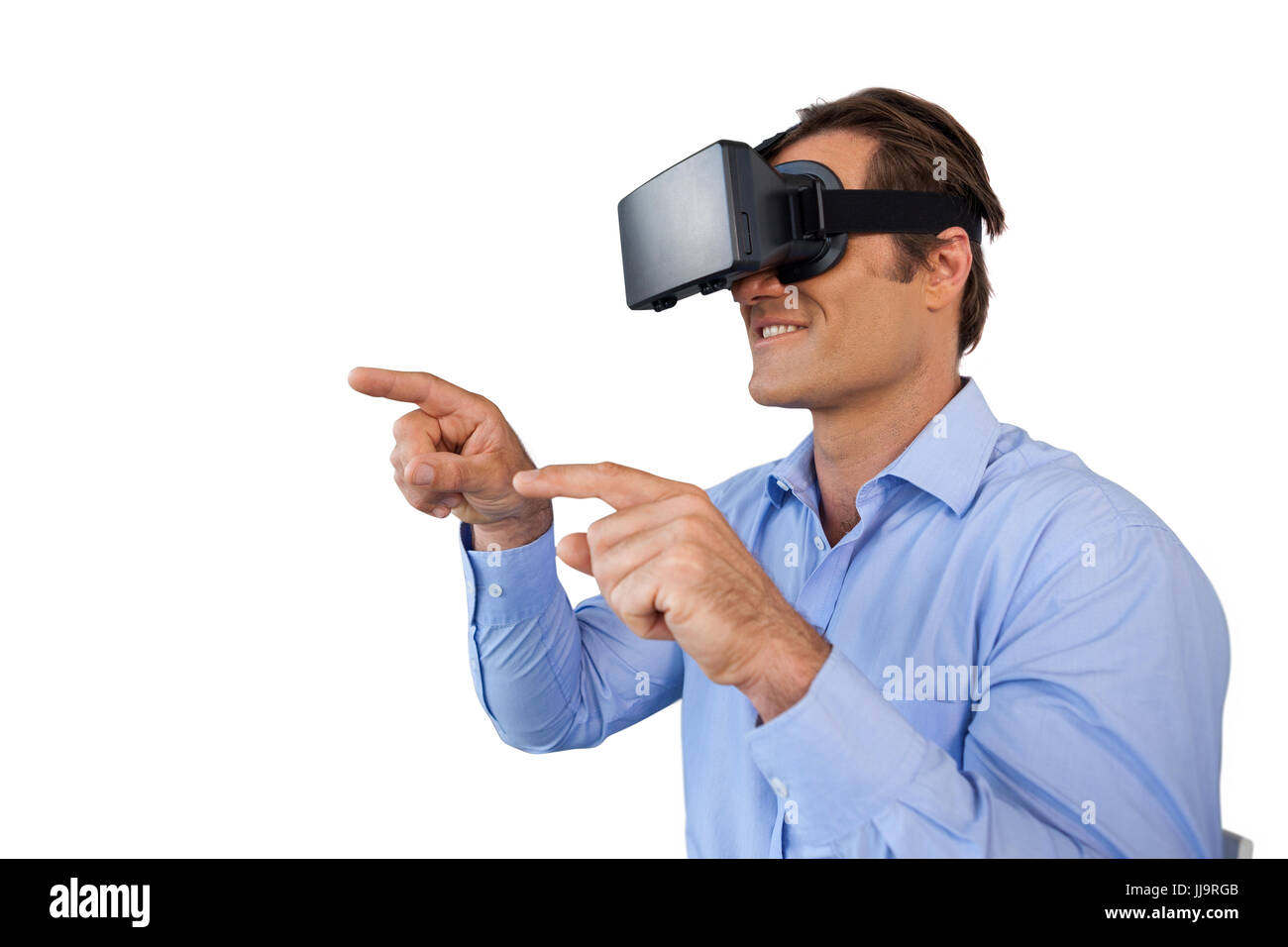 Smiling businessman with gestures using vr glasses while sitting against white background Stock Photo