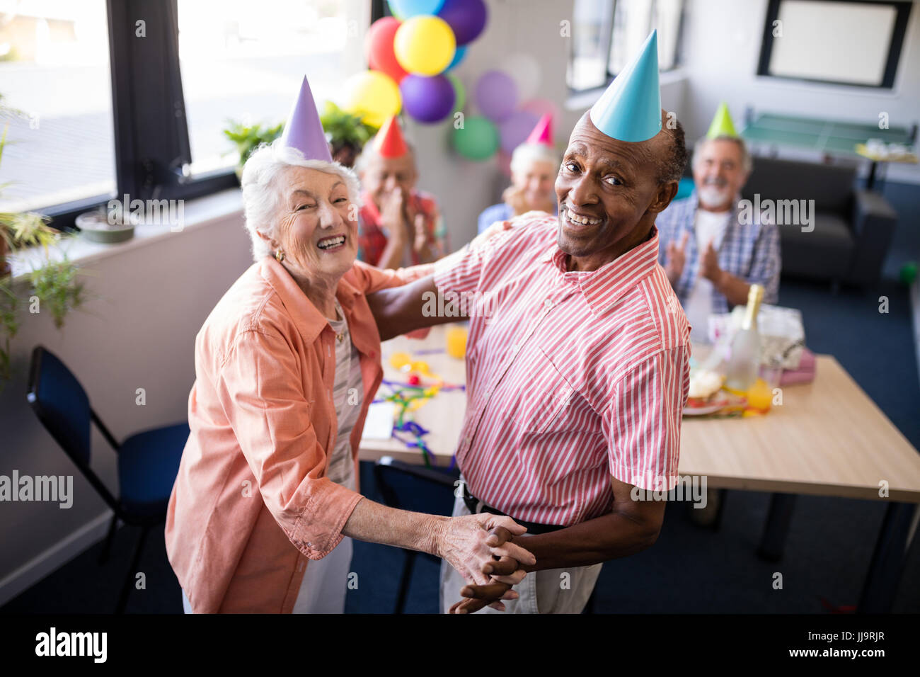 Portrait of happy senior couple dancing by table at birthday party Stock Photo