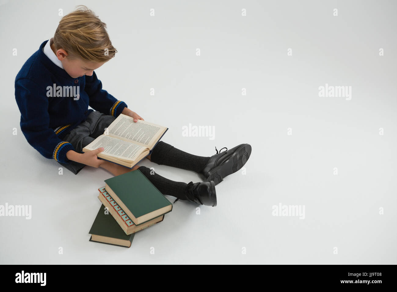 Attentive schoolboy reading book on white background Stock Photo - Alamy