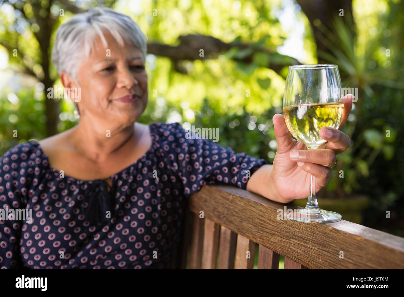 Senior woman holding wine glass at the park Stock Photo - Alamy